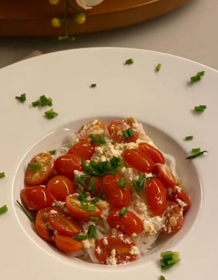 Prato de bifum com tomate cereja, molho de iogurte e cheiro verde servido em prato branco